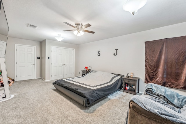 carpeted bedroom with ceiling fan, baseboards, a closet, and visible vents