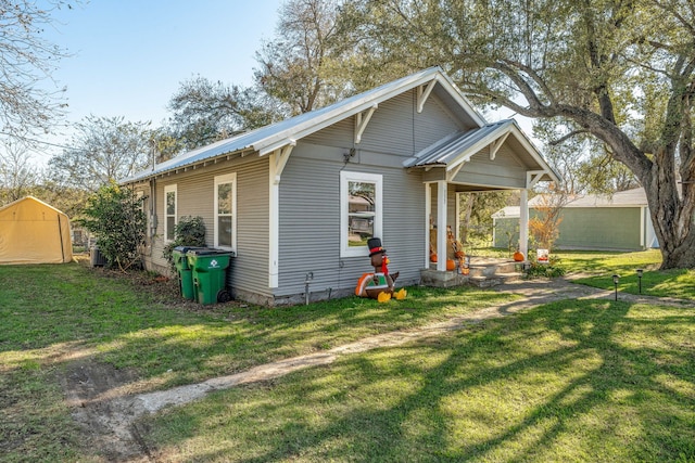 view of home's exterior featuring a lawn, metal roof, an outbuilding, and a storage shed