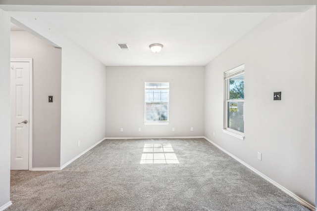 carpeted spare room featuring baseboards, visible vents, and plenty of natural light