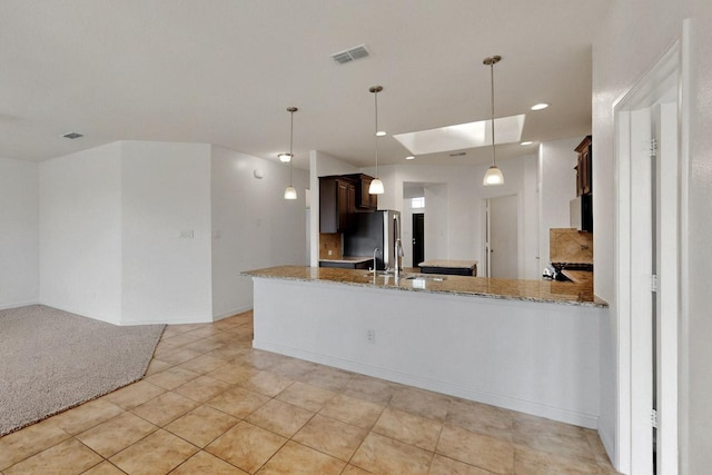 9133 Copper Crossing Dr, Fort Worth, TX 76131 - kitchen featuring light stone countertops, a sink, a skylight, dark brown cabinetry, and a peninsula