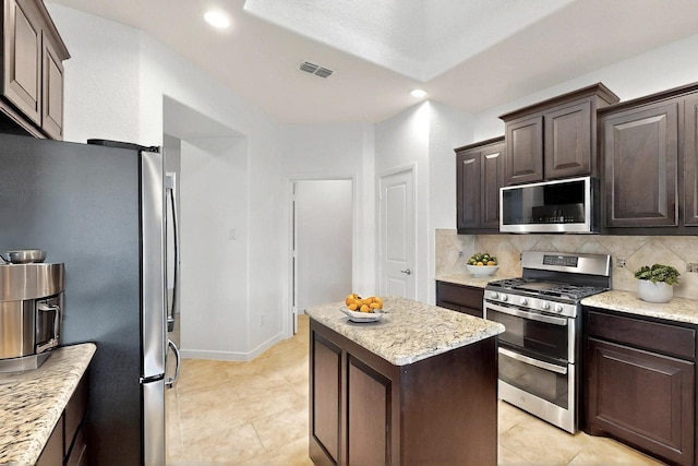 9133 Copper Crossing Dr, Fort Worth, TX 76131 - kitchen with appliances with stainless steel finishes, dark brown cabinets, backsplash, a kitchen island, and recessed lighting