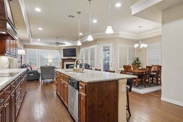 kitchen featuring dishwasher, a sink, open floor plan, a kitchen breakfast bar, and a fireplace