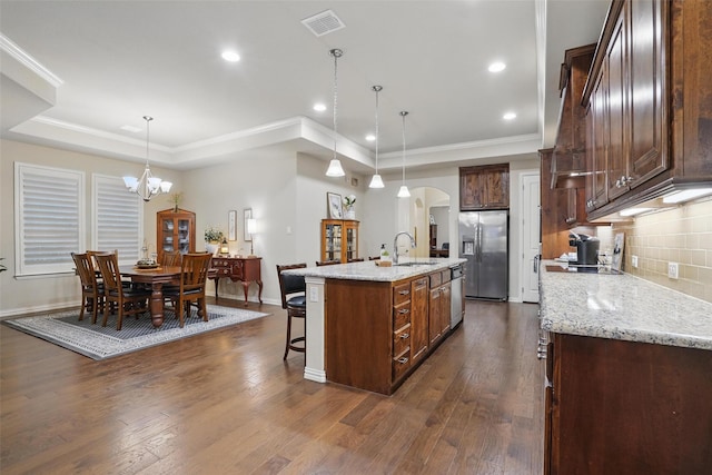 kitchen featuring a kitchen breakfast bar, visible vents, arched walkways, a raised ceiling, and appliances with stainless steel finishes