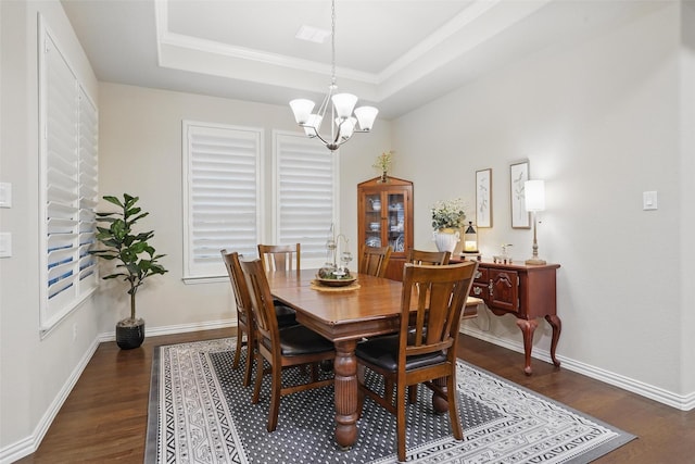 dining area with an inviting chandelier, a raised ceiling, ornamental molding, and wood finished floors