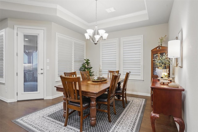 dining space featuring baseboards, ornamental molding, an inviting chandelier, wood finished floors, and a raised ceiling