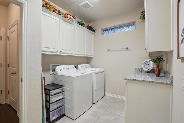 clothes washing area with light tile patterned floors, baseboards, washer and dryer, visible vents, and cabinet space