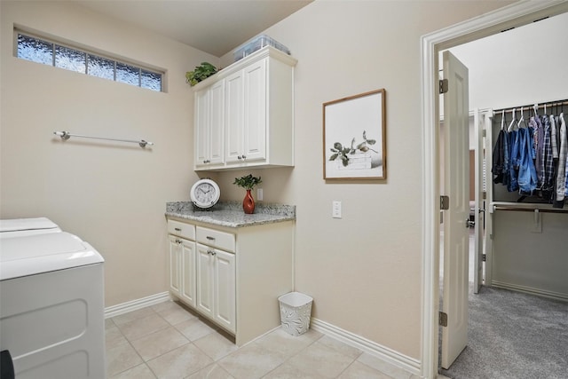 washroom with washing machine and clothes dryer, cabinet space, light tile patterned flooring, and baseboards