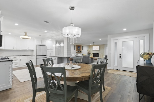 824 Wheelwood Dr, Hurst, TX 76053 - dining area with visible vents, light wood-style flooring, a fireplace, and recessed lighting