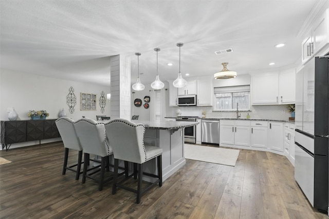 824 Wheelwood Dr, Hurst, TX 76053 - kitchen featuring a sink, a kitchen breakfast bar, dark wood finished floors, visible vents, and appliances with stainless steel finishes