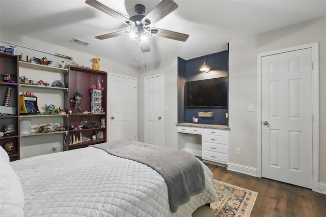 824 Wheelwood Dr, Hurst, TX 76053 - bedroom with baseboards, ceiling fan, visible vents, dark wood-type flooring, and built in desk