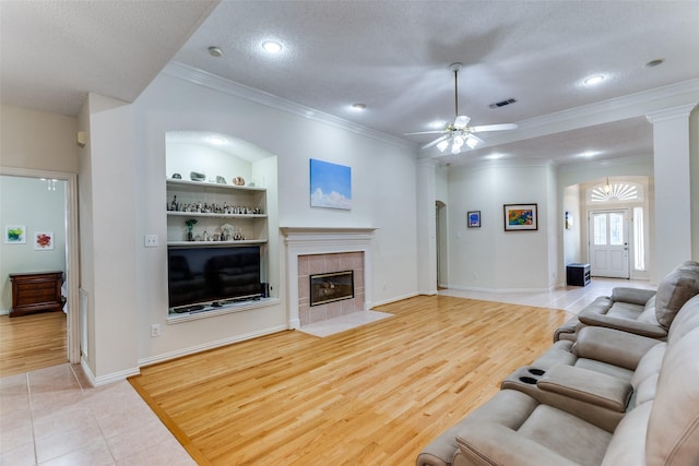 6712 Bluffview Dr, Fort Worth, TX 76132 - living area with built in shelves, crown molding, a ceiling fan, a tile fireplace, and a textured ceiling