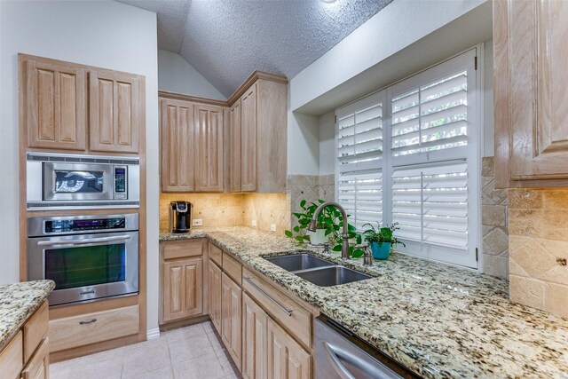 6712 Bluffview Dr, Fort Worth, TX 76132 - kitchen with stainless steel appliances, a sink, light brown cabinets, lofted ceiling, and decorative backsplash