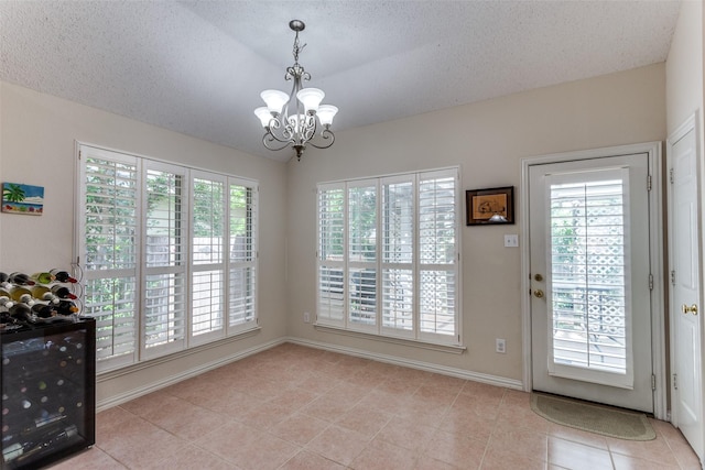 6712 Bluffview Dr, Fort Worth, TX 76132 - doorway to outside with wine cooler, healthy amount of natural light, light tile patterned flooring, a chandelier, and a textured ceiling