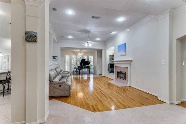 6712 Bluffview Dr, Fort Worth, TX 76132 - living area featuring a ceiling fan, tile patterned flooring, a fireplace, ornamental molding, and a textured ceiling