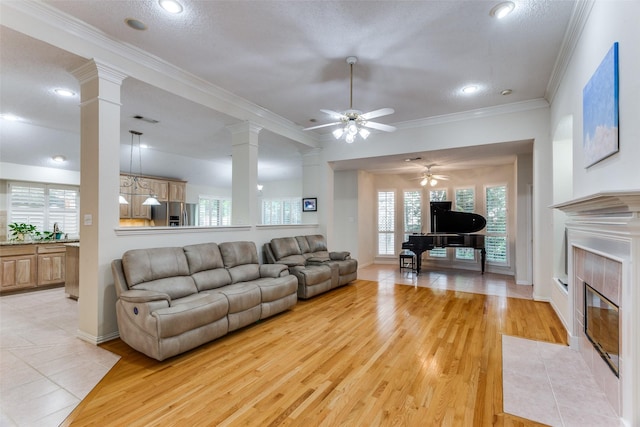 6712 Bluffview Dr, Fort Worth, TX 76132 - living room featuring a ceiling fan, ornate columns, a fireplace, ornamental molding, and light wood finished floors