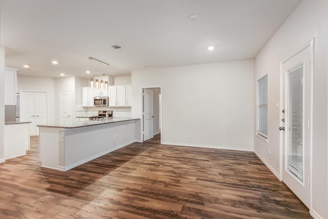 4605 Ashmark Rd, Little Elm, TX 76227 - kitchen with stainless steel microwave, dark wood-style flooring, white cabinetry, and range