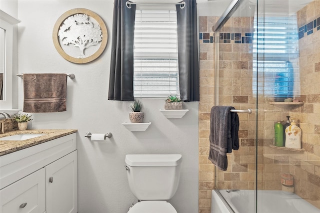 bathroom with vanity, toilet, a wealth of natural light, and combined bath / shower with glass door