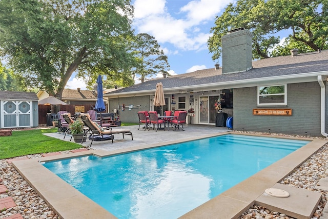 view of swimming pool featuring fence, an outdoor structure, a shed, a patio area, and a fenced in pool