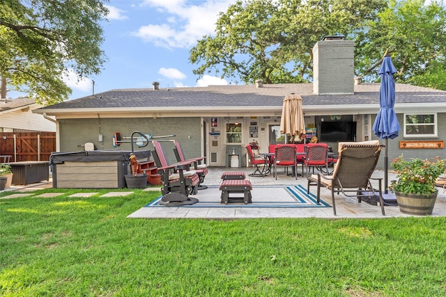 back of house featuring a hot tub, a patio area, fence, brick siding, and a chimney