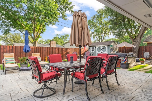 view of patio featuring a fenced backyard, outdoor dining space, a shed, and an outdoor structure