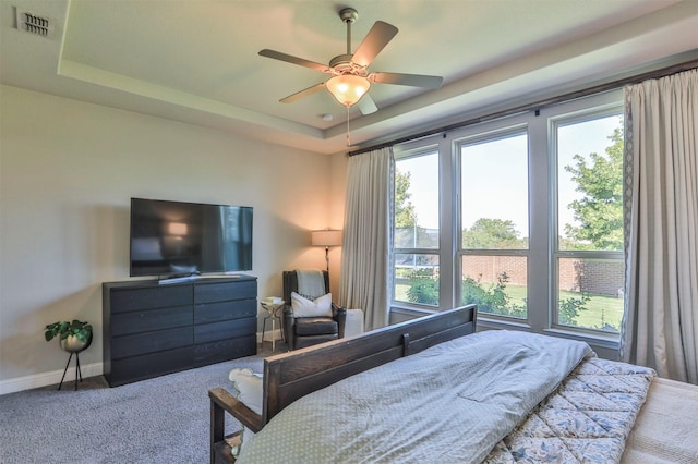 bedroom with carpet, visible vents, a ceiling fan, a tray ceiling, and baseboards