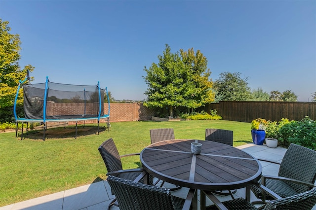 view of patio / terrace featuring a fenced backyard, a trampoline, and outdoor dining area