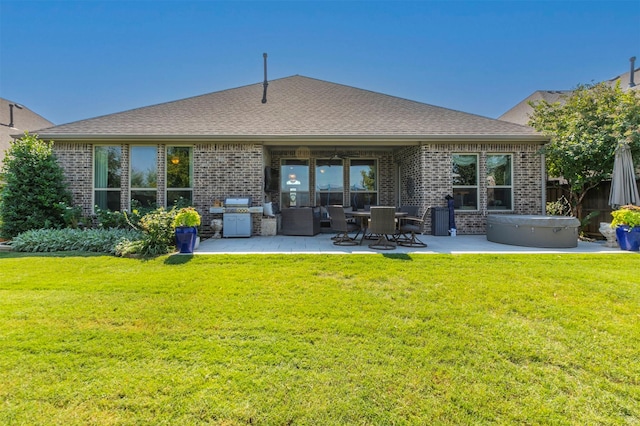 back of house featuring a yard, brick siding, a hot tub, and a patio