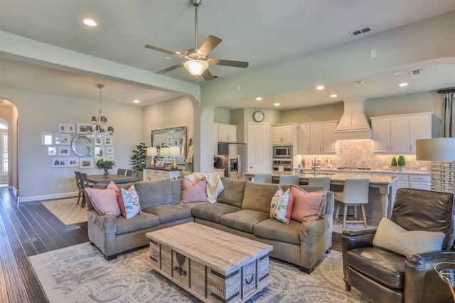 living area featuring recessed lighting, visible vents, ceiling fan with notable chandelier, wood finished floors, and arched walkways