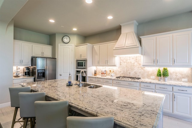 kitchen featuring a breakfast bar area, recessed lighting, custom exhaust hood, a sink, and appliances with stainless steel finishes