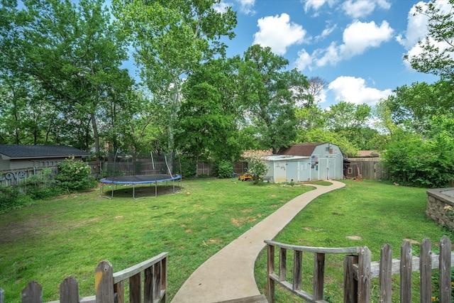 view of yard featuring a trampoline, an outbuilding, a fenced backyard, and a storage unit