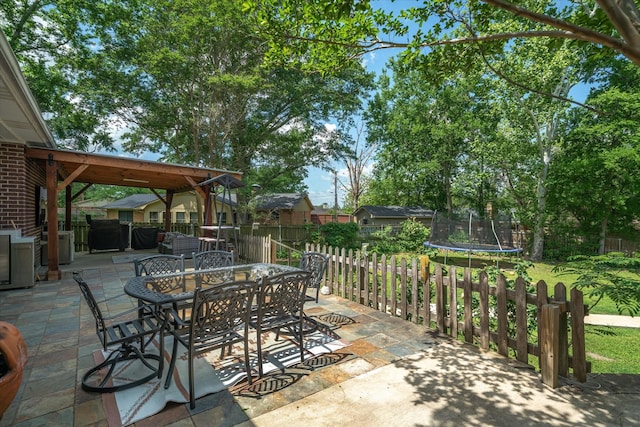 view of patio / terrace featuring a fenced backyard, a trampoline, and outdoor dining space