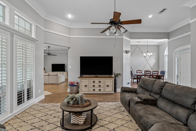 living room featuring crown molding, visible vents, wood finished floors, and ceiling fan with notable chandelier