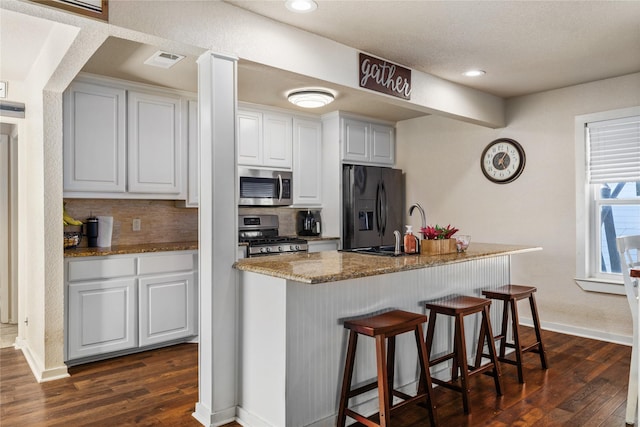 kitchen with dark wood-style flooring, backsplash, visible vents, and appliances with stainless steel finishes