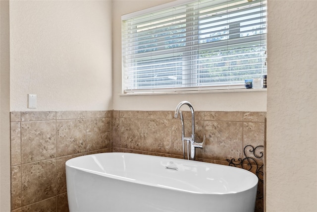 full bathroom with a freestanding bath, plenty of natural light, and a textured wall