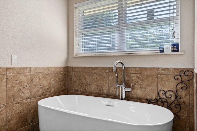 bathroom featuring a sink, a freestanding bath, and plenty of natural light