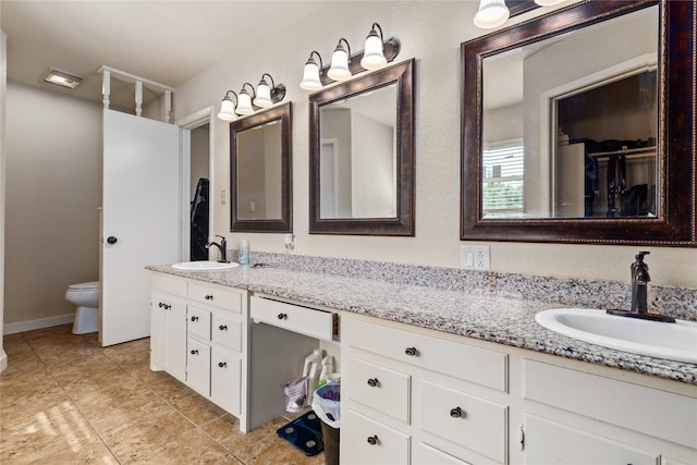 bathroom featuring double vanity, toilet, tile patterned flooring, and a sink