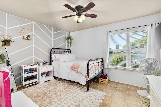 tiled bedroom featuring baseboards and a ceiling fan