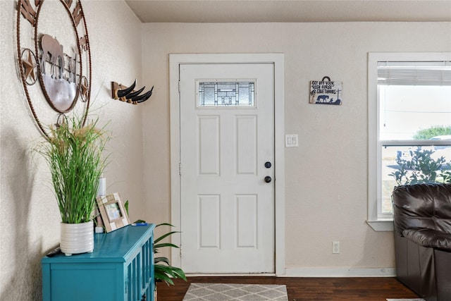 foyer featuring baseboards and dark wood-style floors