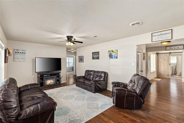 living area featuring visible vents, a barn door, and dark wood-type flooring