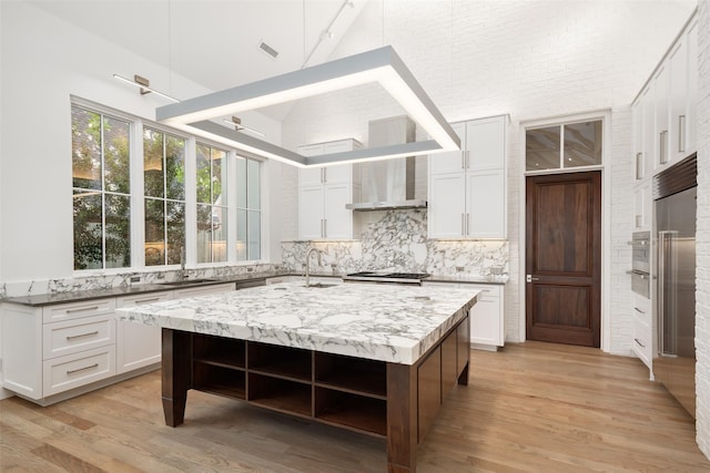 5747 Charlestown Dr, Dallas, TX 75230 - kitchen featuring tasteful backsplash, open shelves, high vaulted ceiling, wall chimney exhaust hood, and light wood-style floors