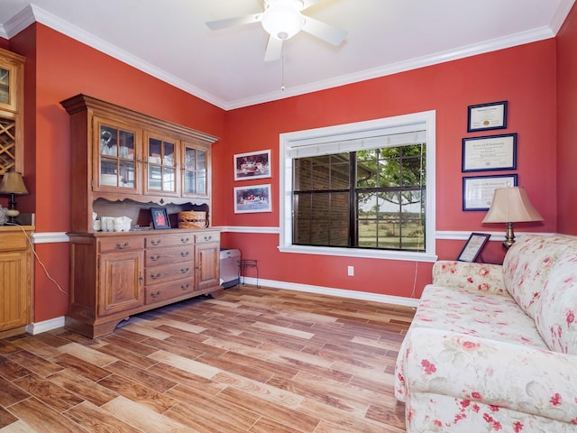 sitting room featuring light wood-type flooring, ornamental molding, ceiling fan, and baseboards