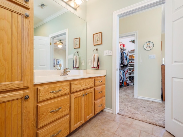 bathroom with crown molding, vanity, tile patterned flooring, ceiling fan, and baseboards