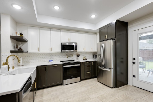 kitchen with a sink, stainless steel appliances, open shelves, and light countertops