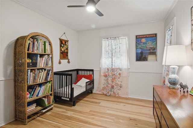 bedroom featuring a wainscoted wall, wood finished floors, and ornamental molding