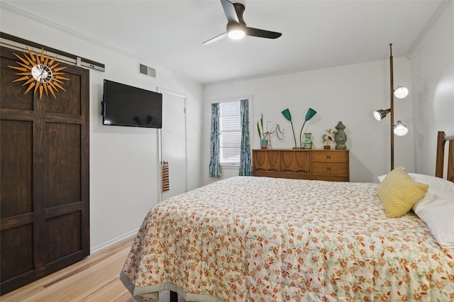 bedroom featuring ceiling fan, visible vents, light wood-style flooring, and ornamental molding