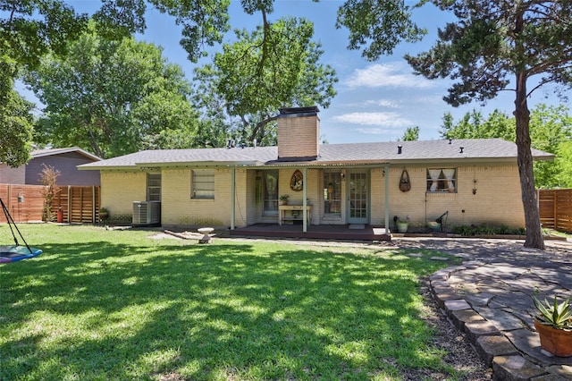 rear view of property with a yard, fence, a chimney, and brick siding