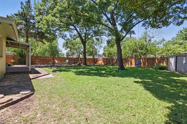 view of yard with an outdoor structure, a shed, a fenced backyard, and a wooden deck
