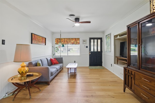 living room with ceiling fan, ornamental molding, visible vents, and light wood-style floors
