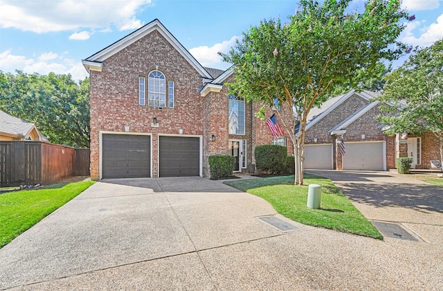 traditional home with concrete driveway, brick siding, fence, and a front yard