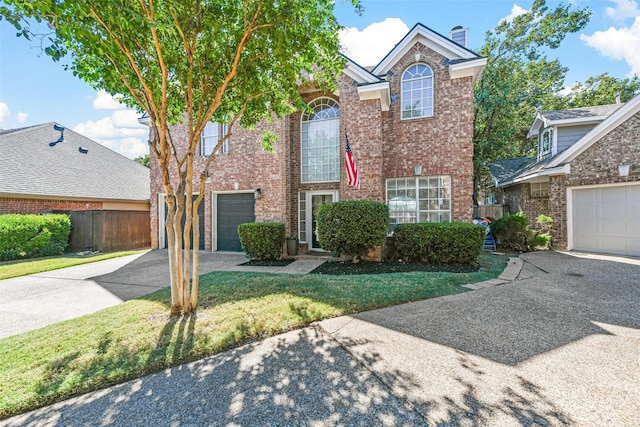traditional home with fence, brick siding, concrete driveway, a front lawn, and a chimney